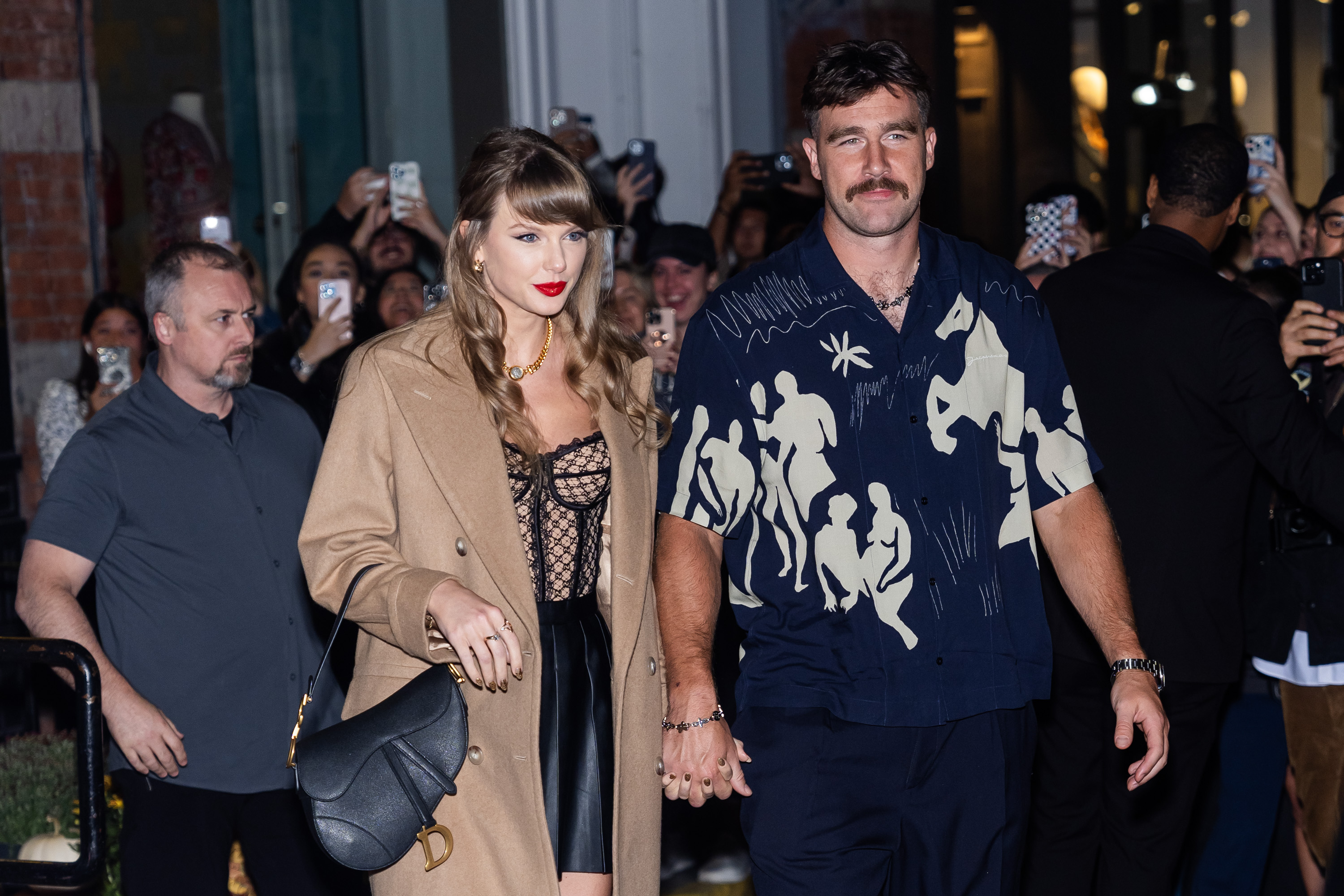 Imagem de Taylor Swift e Travis Kelce saindo de mãos dadas.