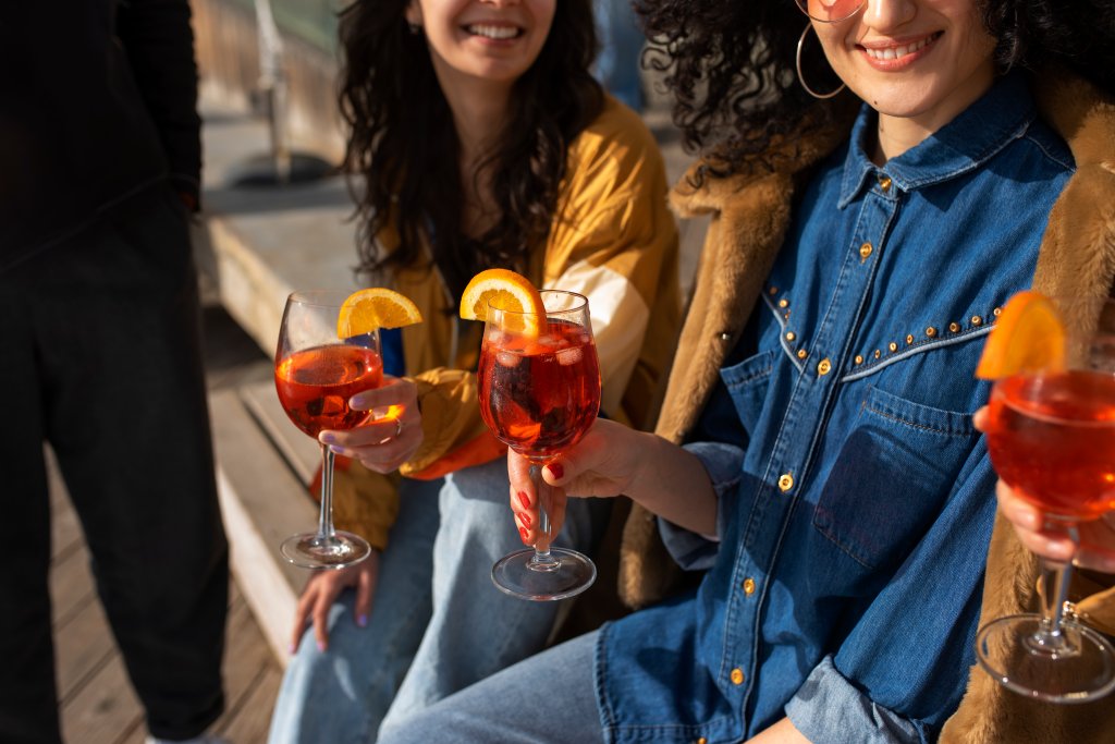 Imagem de amigos segurando copos com drinks nas mãos.