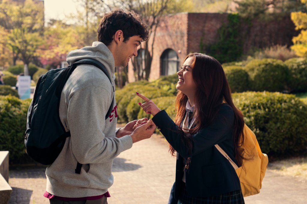 Noah Centineo como Peter Kavinsky e Anna Cathcart como Kitty Song Covey em Com Carinho, Kitty; os dois estão conversando e rindo na área externa da escola durante o dia