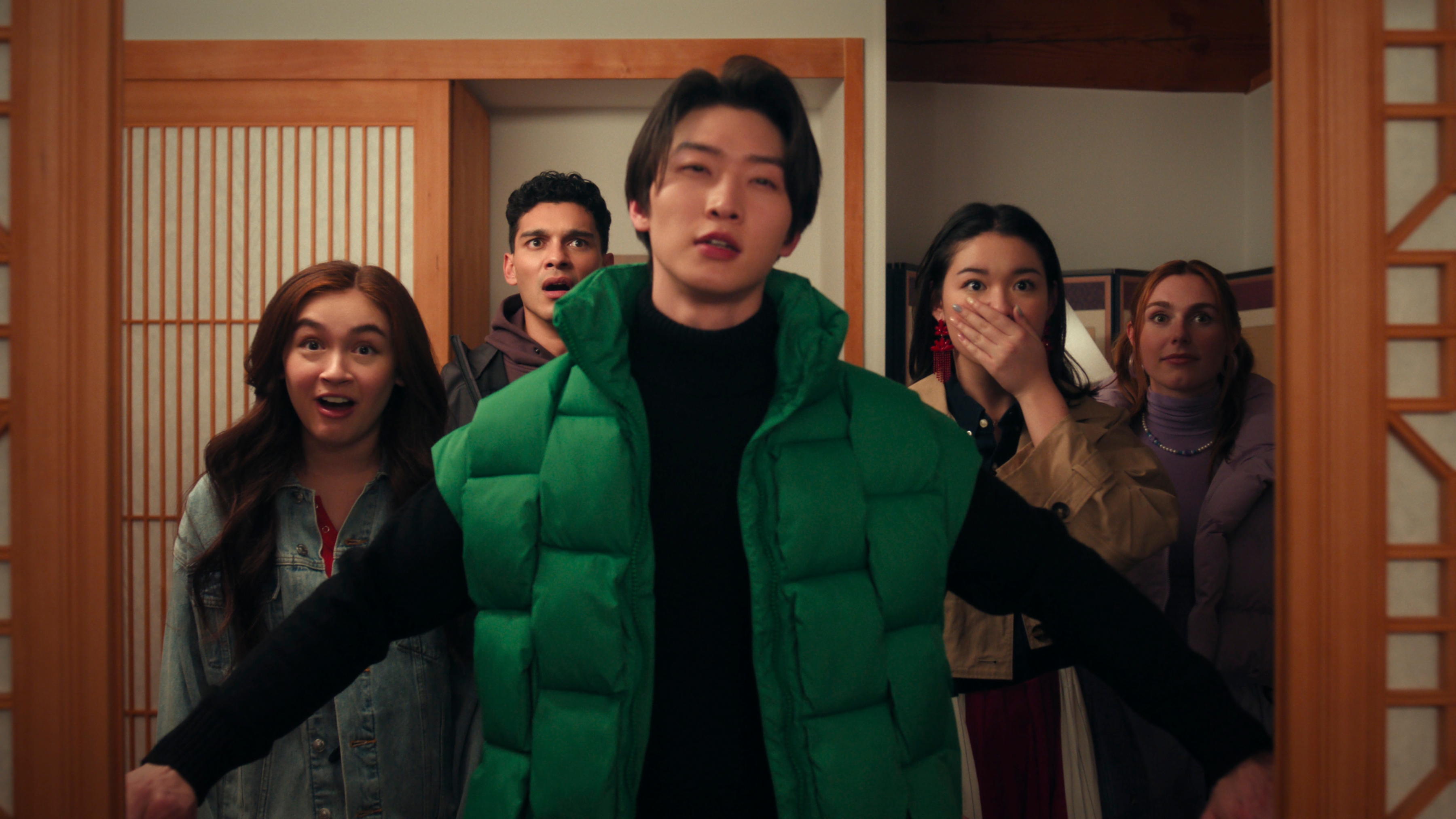 XO_Kitty_n_S2_E4_00_03_38_20R Anna Cathcart como Kitty Song Covey, Anthony Keyvan como Quincy 'Q' Shabazian, Sang Heon Lee como Min Ho Moon, Audrey Huynh como Stella, Jocelyn Shelfo como Madison Miller em Com Carinho, Kitty; eles estão olhando para frente enquanto Min Ho abre a porta; todos estão com expressão de choque e surpresa