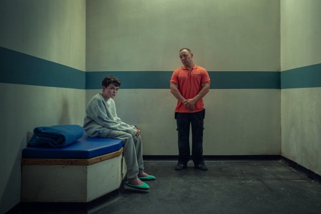 Owen Cooper como Jamie Miller e Stephen Graham como Eddie Miller em Adolescência; os dois estão em uma sala em cena da série
