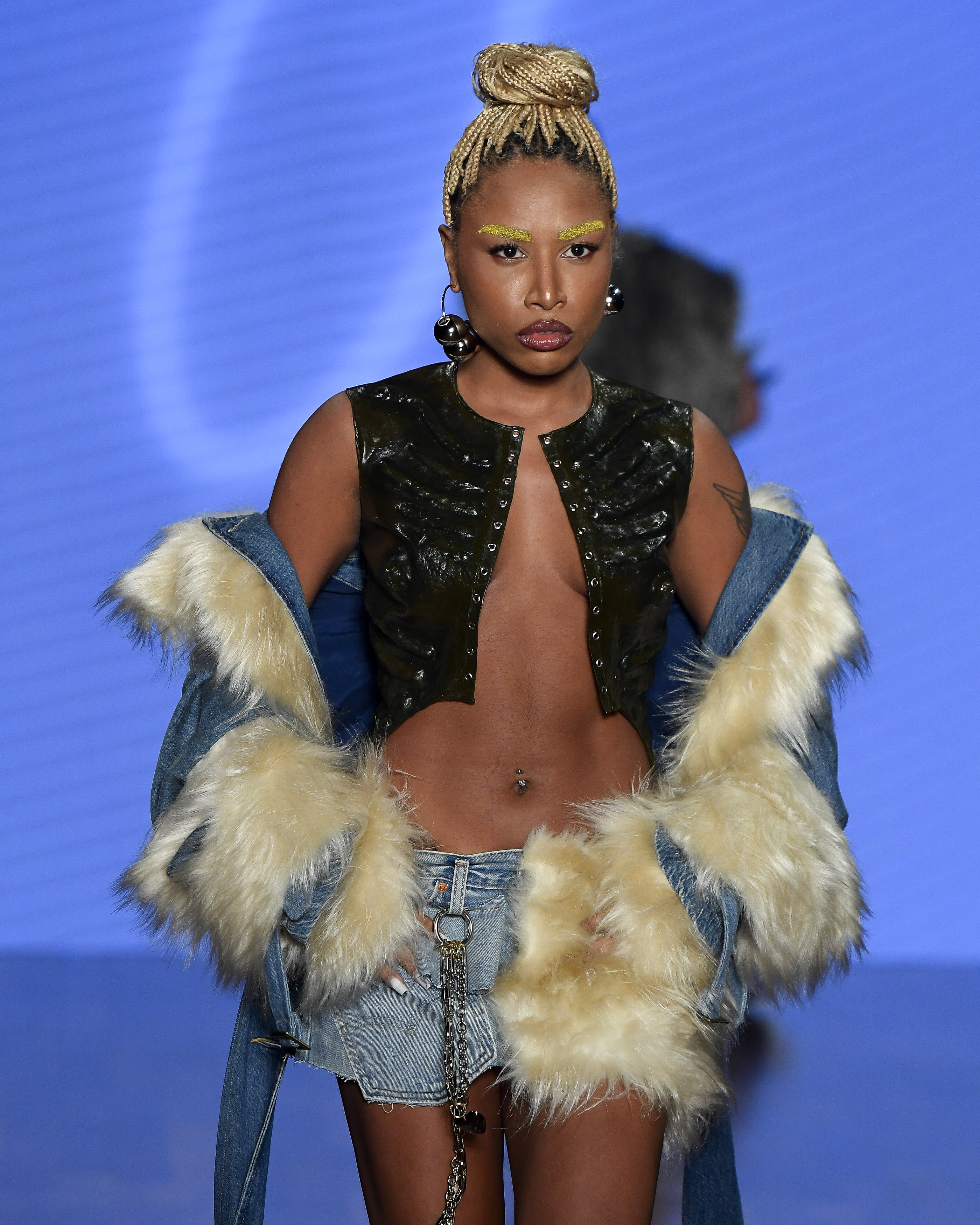Dario Mittmann- SPFW N59Foto: Marcelo Soubhia/ @agfotosite A rapper Ebony na passarela de Dário Mittmann, vestindo um casaco jeans com pelos, saia curta e blusa aberta de látex.