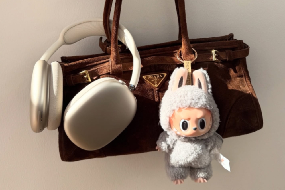 Bolsa Prada com Labubu e headphone da Apple pendurados
