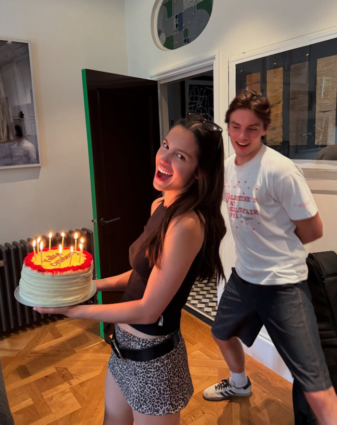 Olivia Rodrigo usando minissaia de animal print ao lado de Louis Partridge