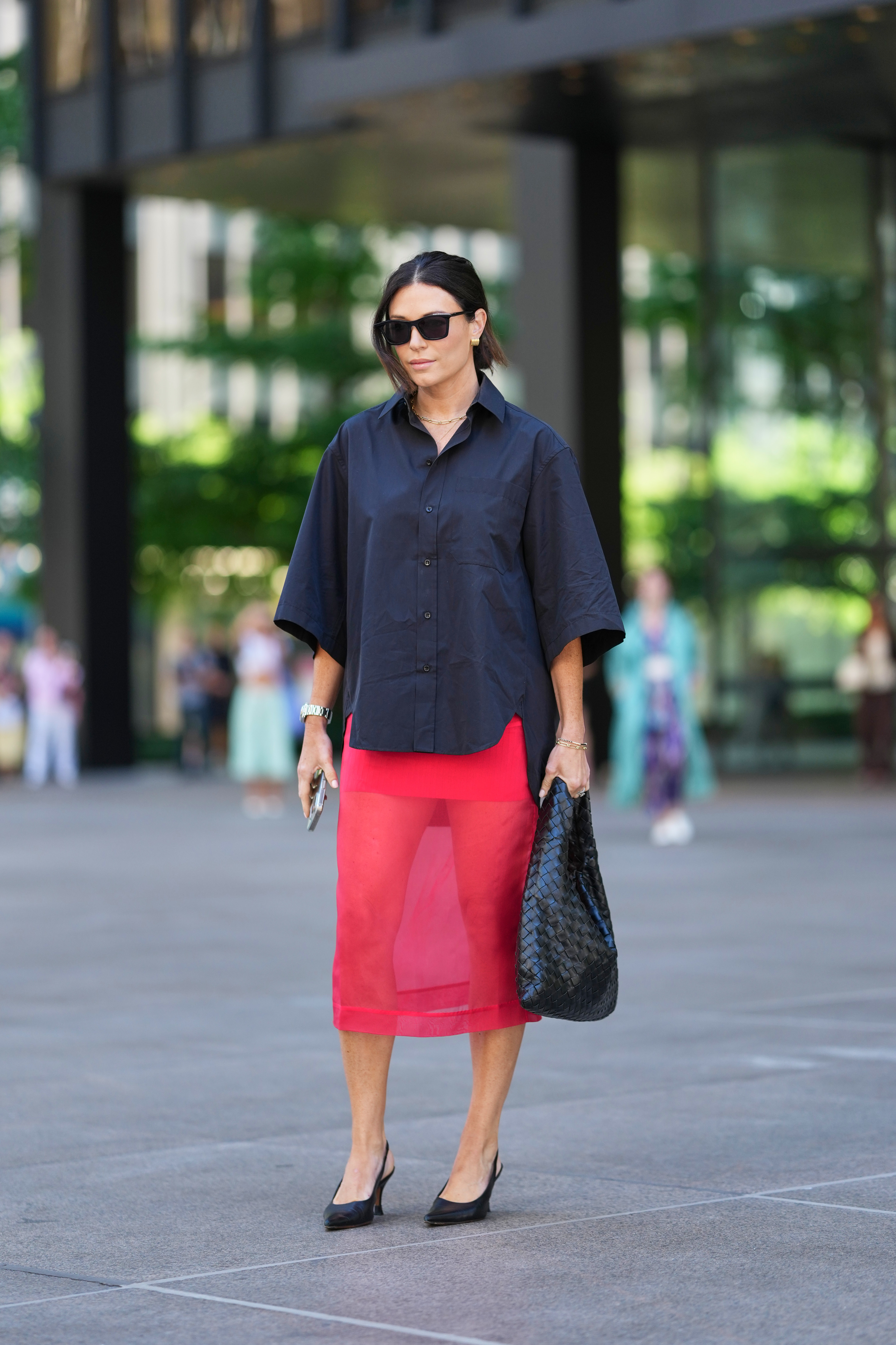 Street Style – September 2025 New York Fashion Week Mulher em Nova York usando saia transparente vermelha e camiseta preta com óculos de sol