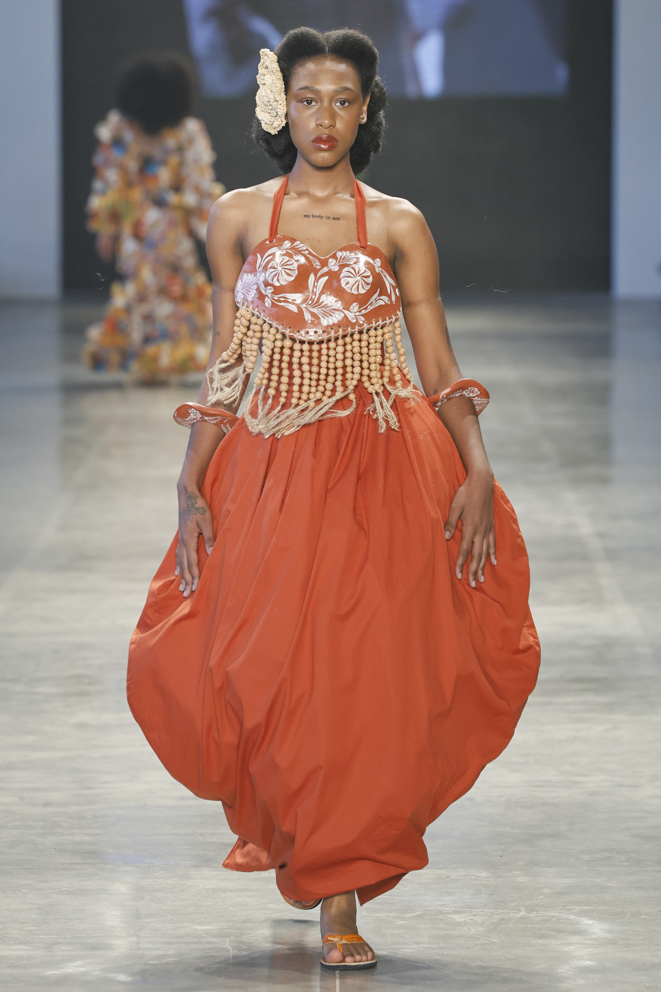 Meninos Rei SPFW N60 Foto: Ze Takahashi/ @agfotosite Modelo desfilando no desfile da marca Meninos Rei SPFW N60 com look laranja, pele iluminada e lábios avermelhados