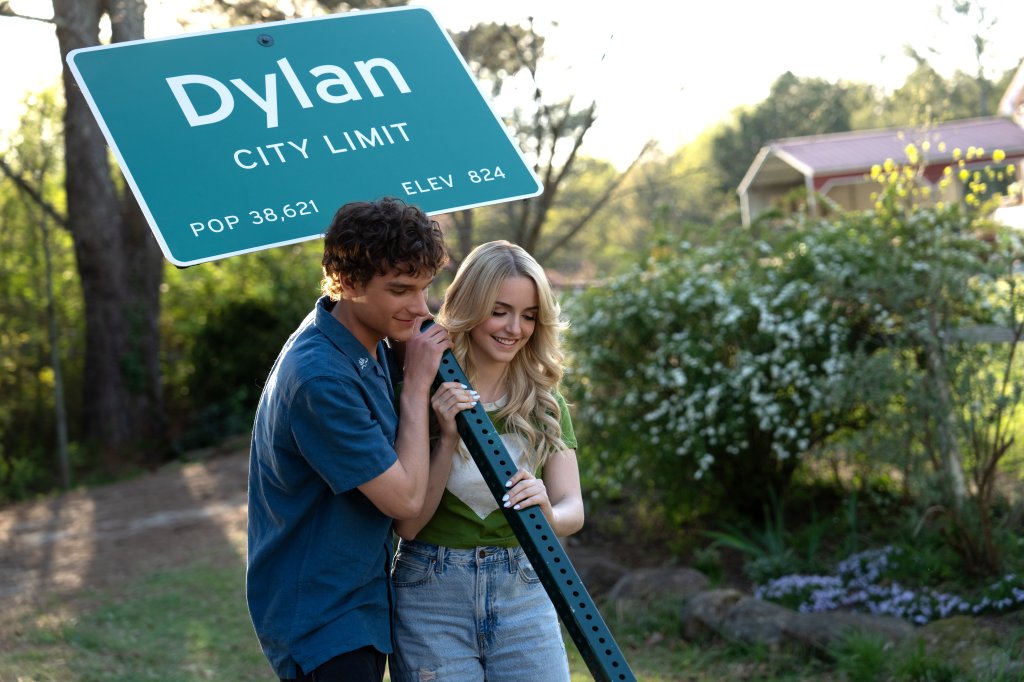 Mason Thames como Miller, e McKenna Grace como Clara segurando placa da cidade em cena de Se Não Fosse Você
