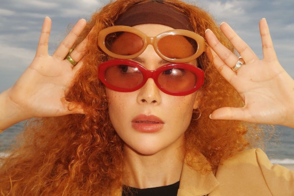 Garota usando dois óculos de sol, um em cima do outro e olhando para o lado