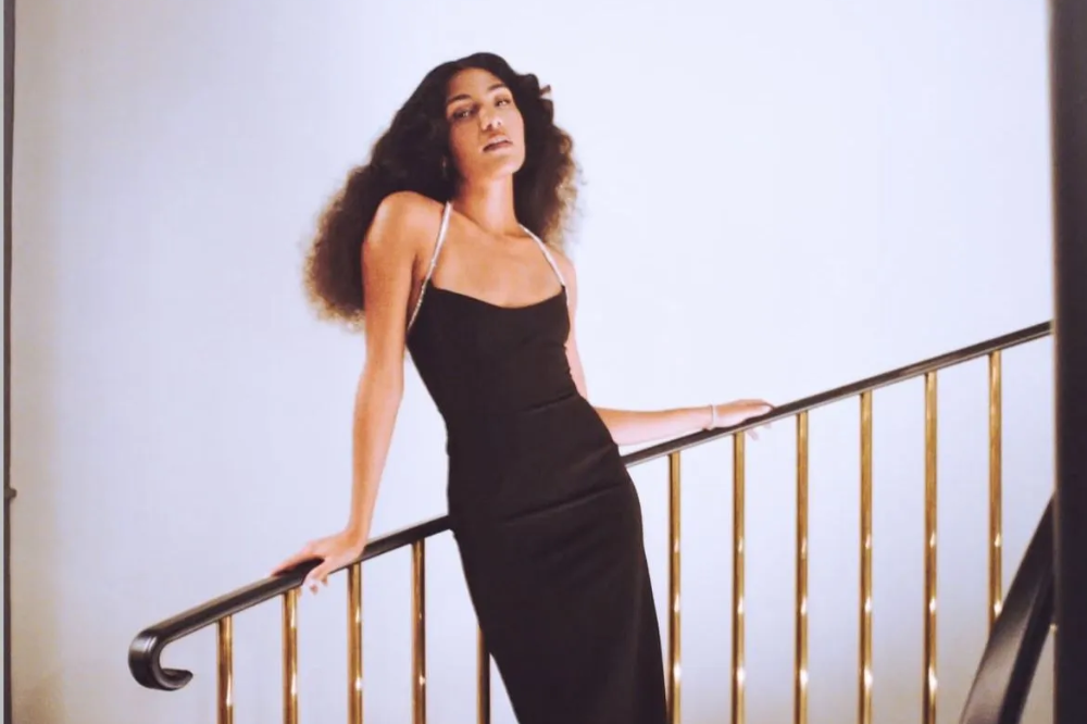 Olivia Dean com vestido preto em escada