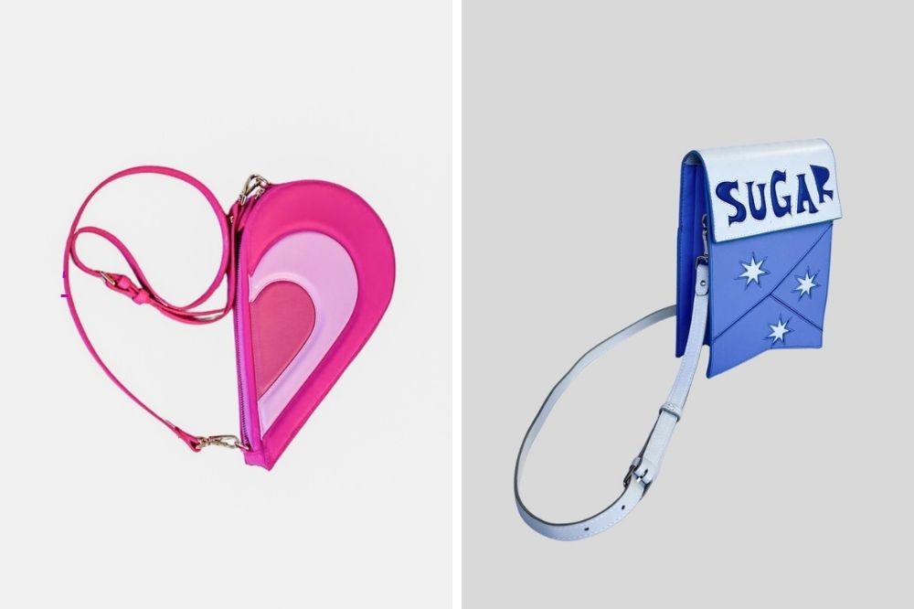 Duas bolsas de ombro em fundo cinza claro. À esquerda, uma bolsa em formato de coração com tons de rosa e alça fina. À direita, uma bolsa azul e branca com a palavra "SUGAR" e três estrelas brancas, com alça branca
