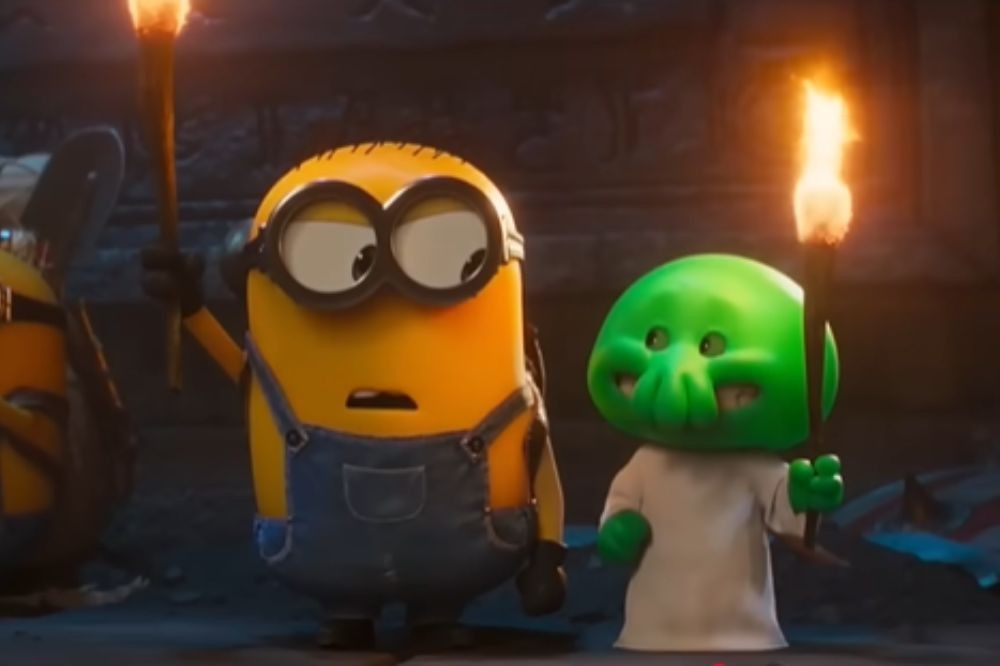 Um Minion amarelo com óculos e macacão jeans, segurando uma tocha acesa, olha assustado para a direita, ao lado de um personagem verde com rosto de polvo e túnica branca, também segurando uma tocha, em um ambiente escuro