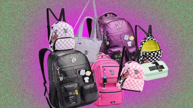 Variedade de mochilas e bolsas escolares coloridas, incluindo modelos xadrez rosa, lilás e preto, além de mochilas roxa e rosa vibrantes, e uma bolsa cinza, todas com o logo CH e alguns chaveiros decorativos, sobre um fundo gradiente de verde e roxo