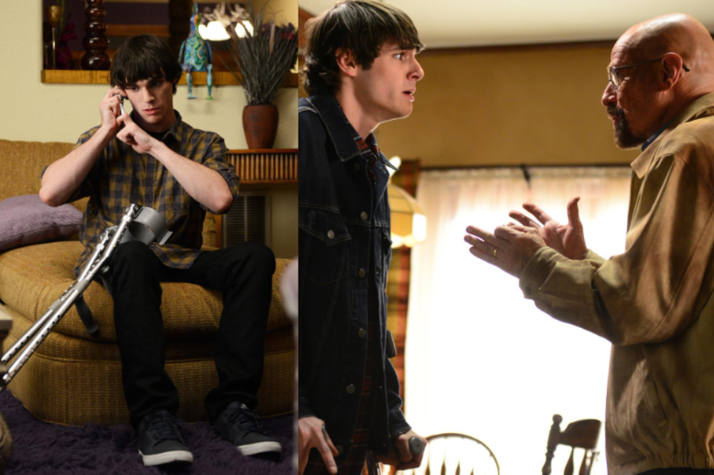 O ator RJ Mitte, com cabelo castanho e camisa xadrez, sentado em um sofá marrom com muletas ao lado, falando ao telefone. Ao lado, o ator Bryan Cranston, careca e de óculos, gesticula com as mãos enquanto conversa com Mitte, que veste jaqueta jeans e parece surpreso