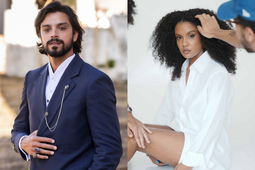 À esquerda, um homem de barba e cabelo escuro, vestindo terno azul-marinho e camisa branca, com um broche de corrente. À direita, uma mulher de pele escura e cabelo cacheado, usando camisa branca oversized, enquanto uma mão ajusta seu cabelo