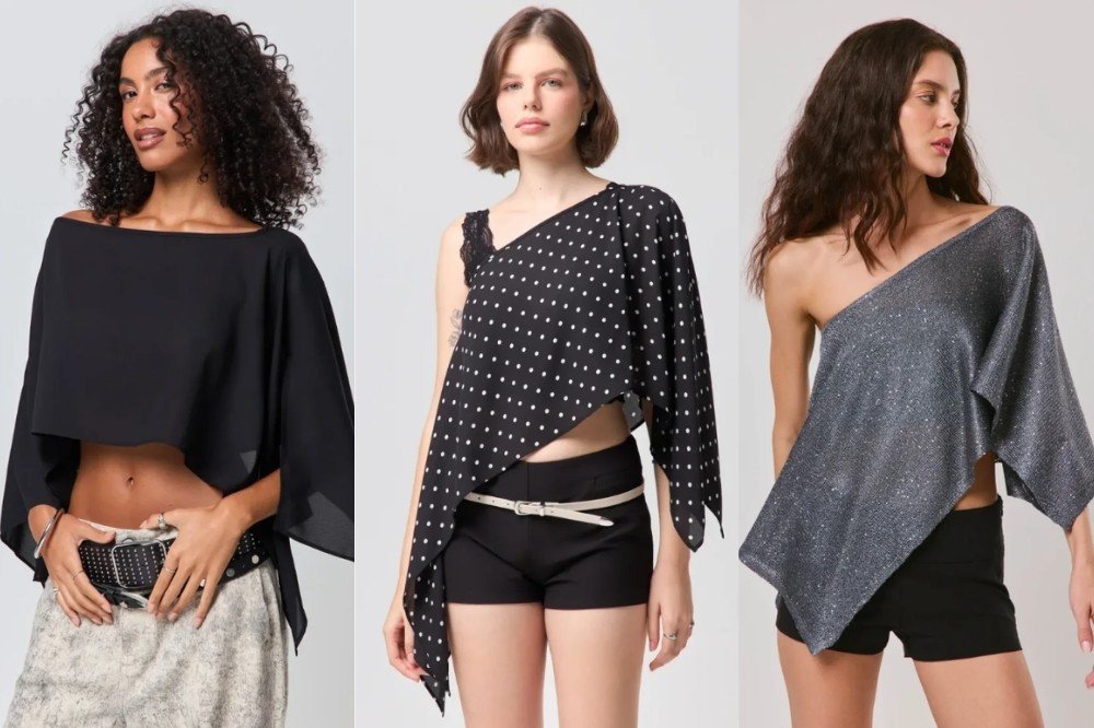 Três mulheres posam com blusas assimétricas. A primeira, de cabelo cacheado, veste blusa preta de manga larga e calça estampada. A segunda, de cabelo curto, usa blusa preta de bolinhas brancas com alça de renda e shorts preto. A terceira, de cabelo ondulado, veste blusa cinza brilhante de um ombro só e shorts preto