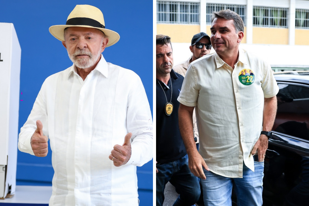 Lula, de chapéu de palha e camisa branca, faz sinal de positivo ao lado de Flávio Bolsonaro, de camisa clara e broche verde com o número 22