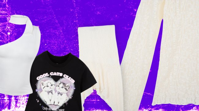Três peças de roupa sobre fundo roxo texturizado: um top branco de um ombro só, uma camiseta preta com estampa de dois gatinhos em um coração e uma calça comprida bege com textura enrugada